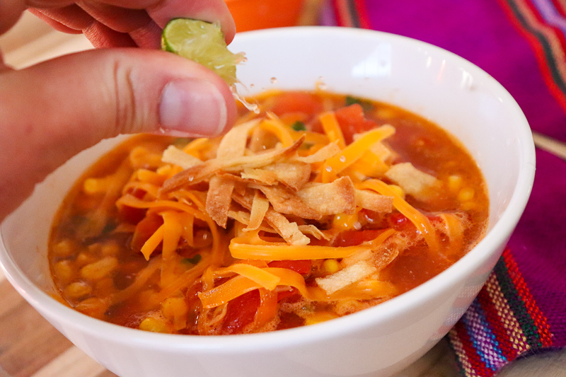 Squeezing lime juice onto chicken tortilla soup