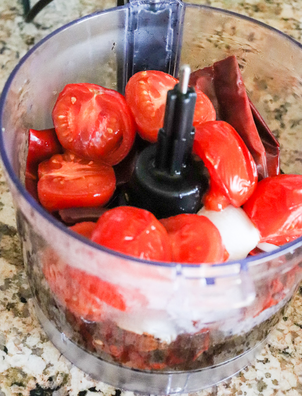 Food processor with tomatoes, onion, red chiles, and garlic
